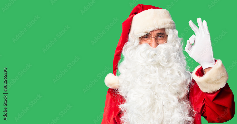 Middle age handsome man wearing Santa Claus costume and beard standing smiling positive doing ok sign with hand and fingers. Successful expression. Middle age handsome man wearing Santa Claus costume and beard standing smiling positive doing ok sign with hand and fingers. Successful expression.