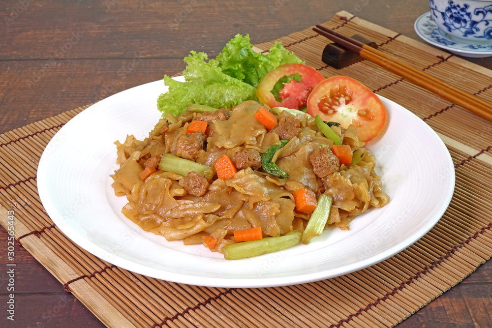 Stir fried flat noodle with black soy sauce, tofu, carrots and green vegetables. Vegetarian food for vegetarian festival. Thai style stir fry flat noodle. (Pad See Ew) Selective focus with copy space Stir fried flat noodle with black soy sauce, tofu, carrots and green vegetables. Vegetarian food for vegetarian festival. Thai style stir fry flat noodle. (Pad See Ew) Selective focus with copy space