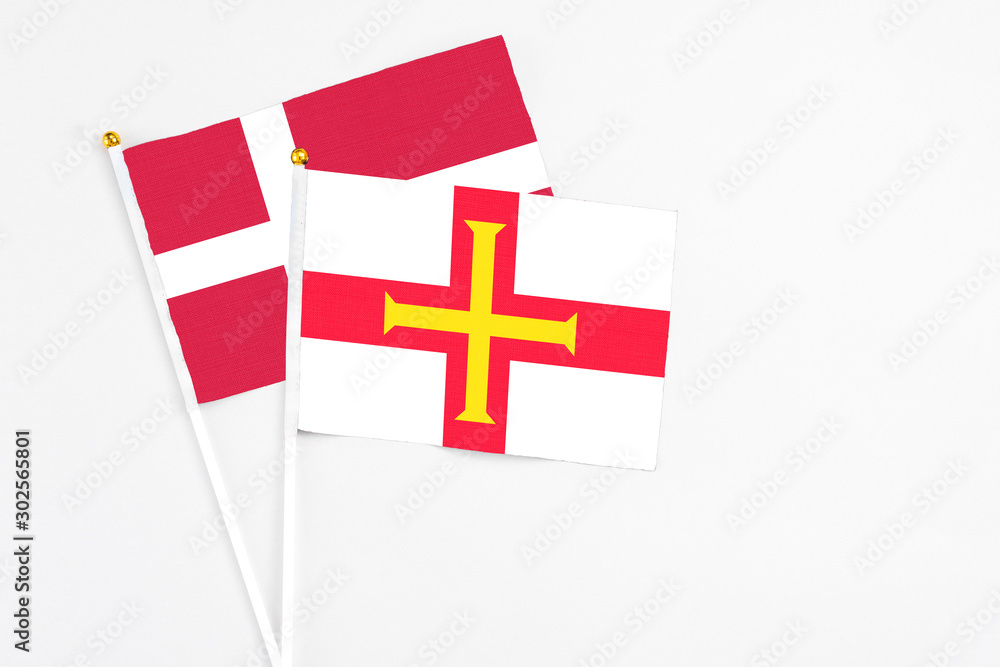 Guernsey and Denmark stick flags on white background. High quality fabric, miniature national flag. Peaceful global concept.White floor for copy space.