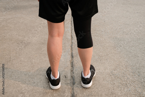 Back side of runner woman wearing knee support to prevent and reduce knee pain from running. This helps support the knee, and can control pain and swelling.
