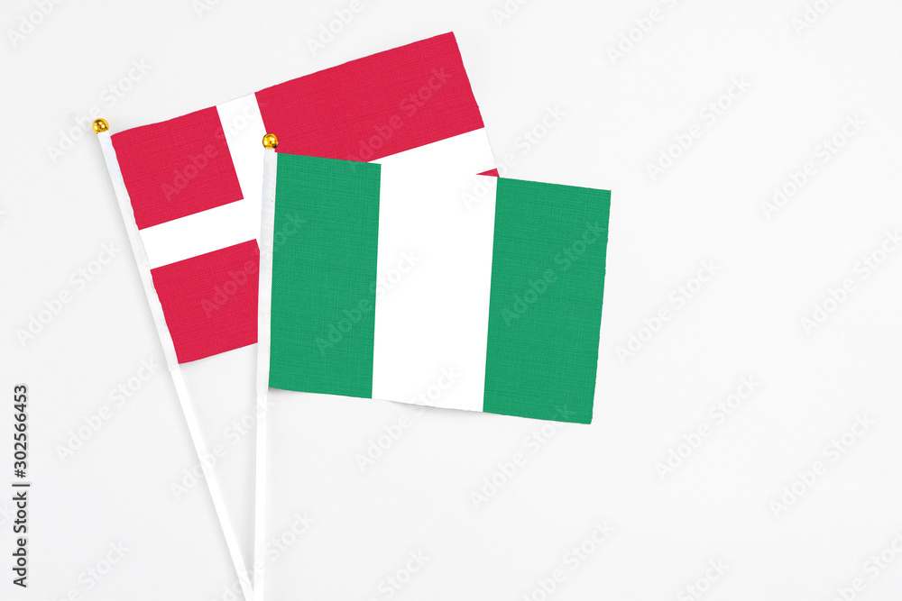 Nigeria and Denmark stick flags on white background. High quality fabric, miniature national flag. Peaceful global concept.White floor for copy space. Nigeria and Denmark stick flags on white background. High quality fabric, miniature national flag. Peaceful global concept.White floor for copy space.