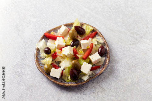 Salad with Green and Kalamata Olives, Red Pepper and Feta Cheese on Bright Stone Background. Healthy Snack Idea. Copy space. 
