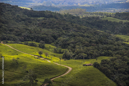 Landscape with many trees in mountains and a road that passes in the middle with a shed on the side which can be seen from afar
