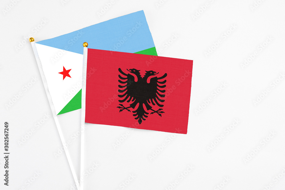 Fototapeta premium Albania and Djibouti stick flags on white background. High quality fabric, miniature national flag. Peaceful global concept.White floor for copy space.