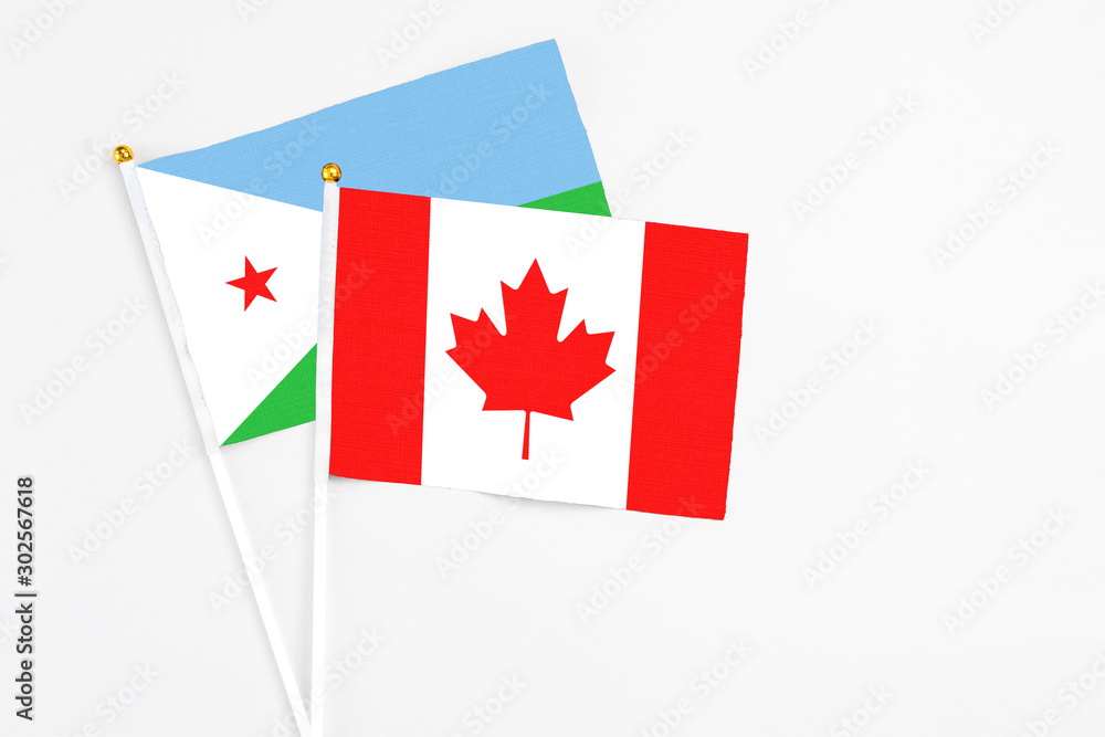 Obraz premium Canada and Djibouti stick flags on white background. High quality fabric, miniature national flag. Peaceful global concept.White floor for copy space.