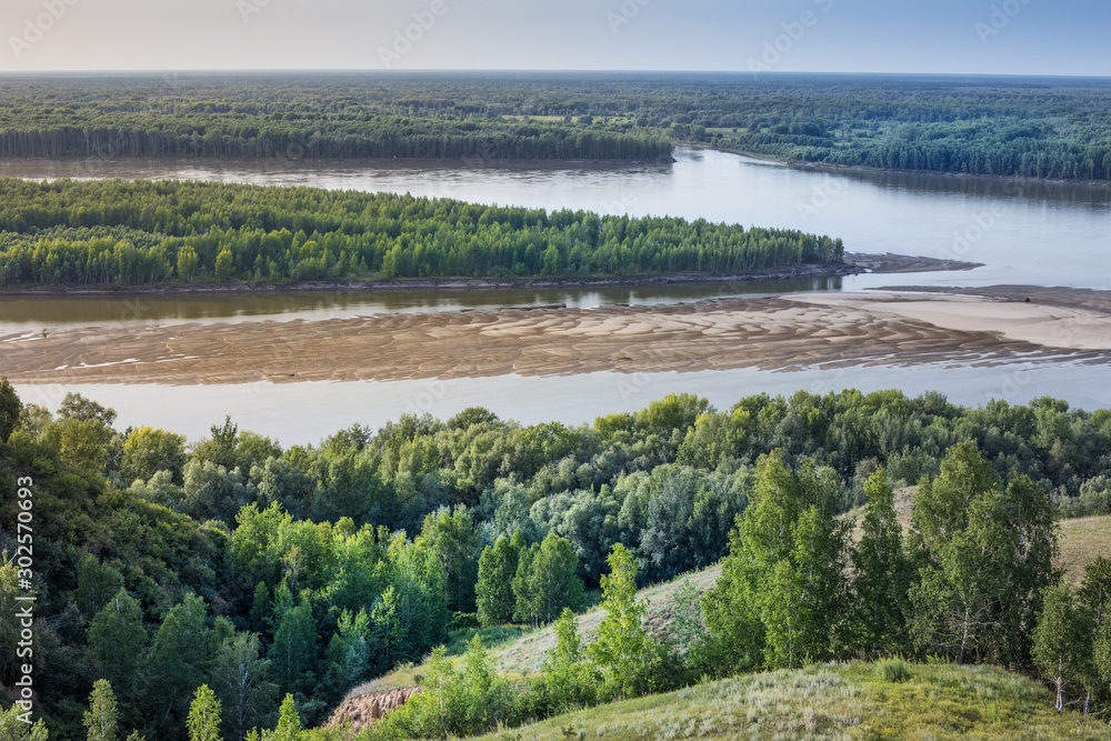 The Ob river, Altai Krai, Siberia, Russia. Summer river landscape, view of the river from a height. Shoals on the Ob river in August.