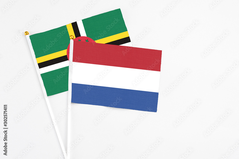 Netherlands and Dominica stick flags on white background. High quality fabric, miniature national flag. Peaceful global concept.White floor for copy space. Netherlands and Dominica stick flags on white background. High quality fabric, miniature national flag. Peaceful global concept.White floor for copy space.