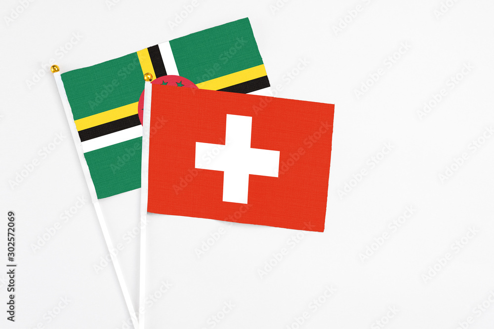 Switzerland and Dominica stick flags on white background. High quality fabric, miniature national flag. Peaceful global concept.White floor for copy space.