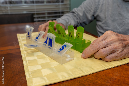 Elderly man sorting daily medication on kitchen table