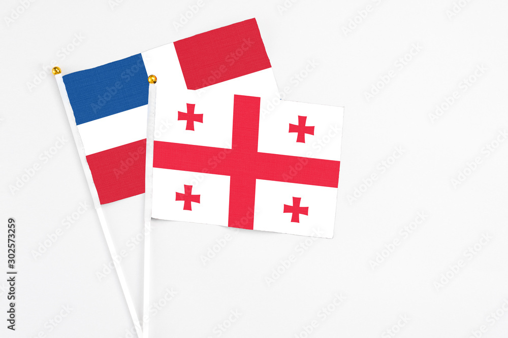 Georgia and Dominican Republic stick flags on white background. High quality fabric, miniature national flag. Peaceful global concept.White floor for copy space.