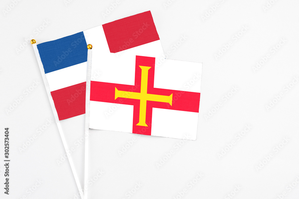 Guernsey and Dominican Republic stick flags on white background. High quality fabric, miniature national flag. Peaceful global concept.White floor for copy space.
