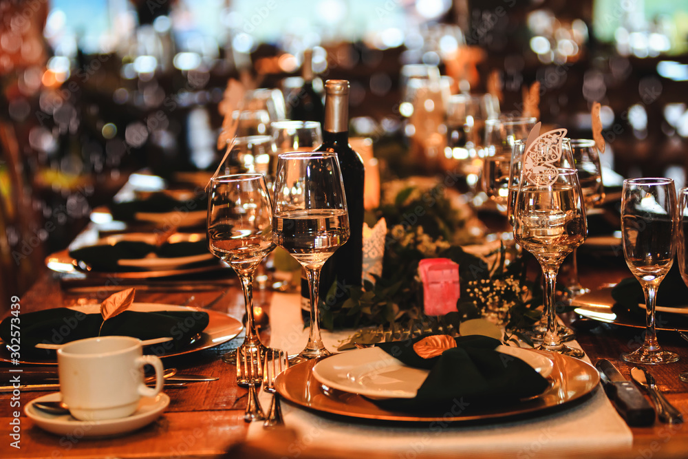 Beautiful dinner table setting. Vintage decoration of reception table.  Elegant arrangement of the holiday tableware. Wine glasses, plates, forks  and green briefcases for event celebration. Stock Photo | Adobe Stock