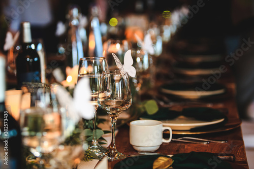 Fototapeta Naklejka Na Ścianę i Meble -  Banquet or holiday background in a rustic atmosphere. Dinner table setting. Vintage decoration of reception table. Elegant arrangement of the holiday tableware. Wine glasses, plates, forks.
