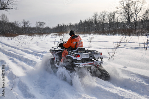 ATV on tracks ride on a snowy road in the taiga