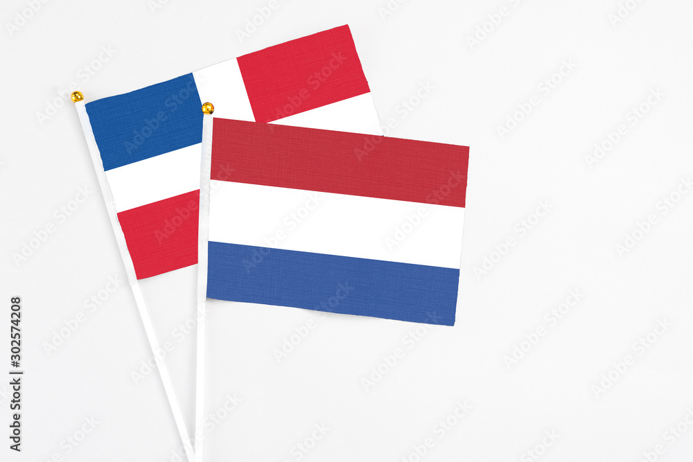 Netherlands and Dominican Republic stick flags on white background. High quality fabric, miniature national flag. Peaceful global concept.White floor for copy space. Netherlands and Dominican Republic stick flags on white background. High quality fabric, miniature national flag. Peaceful global concept.White floor for copy space.