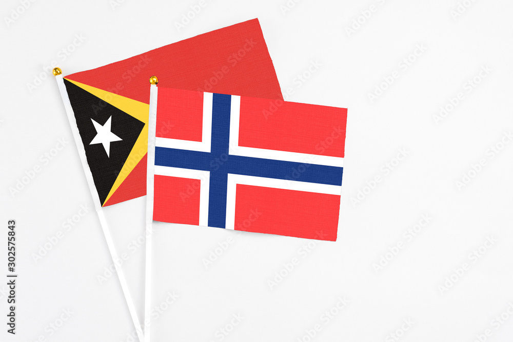 Bouvet Islands and East Timor stick flags on white background. High quality fabric, miniature national flag. Peaceful global concept.White floor for copy space.