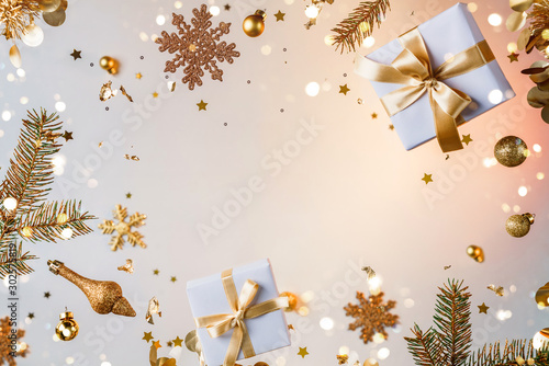 Merry Christmas and New Year background. Xmas holiday card made of flying decorations, gold fir branches, balls, snowflakes, sparkles, gift boxes, bokeh, light on golden background. Selective focus