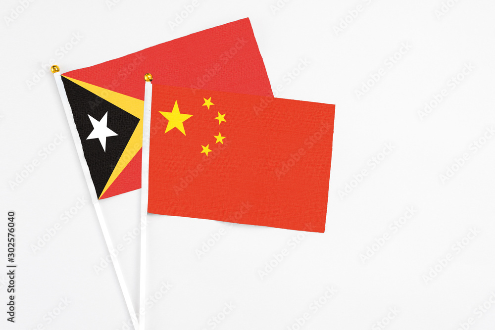 China and East Timor stick flags on white background. High quality fabric, miniature national flag. Peaceful global concept.White floor for copy space. China and East Timor stick flags on white background. High quality fabric, miniature national flag. Peaceful global concept.White floor for copy space.