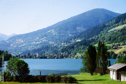 Panorama of lake Field am See at Carinthia in Austria. Landscape with pond and blue sky in spring or summer. Scenery in green Alps of Europe. Countryside with Alpine mountains. Nature with water