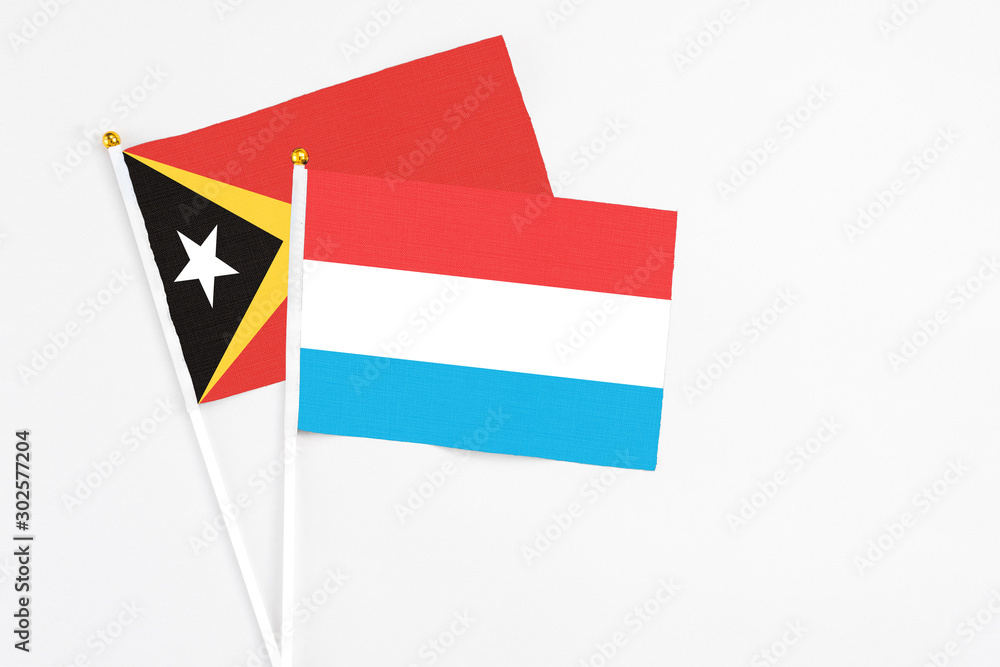 Luxembourg and East Timor stick flags on white background. High quality fabric, miniature national flag. Peaceful global concept.White floor for copy space. Luxembourg and East Timor stick flags on white background. High quality fabric, miniature national flag. Peaceful global concept.White floor for copy space.