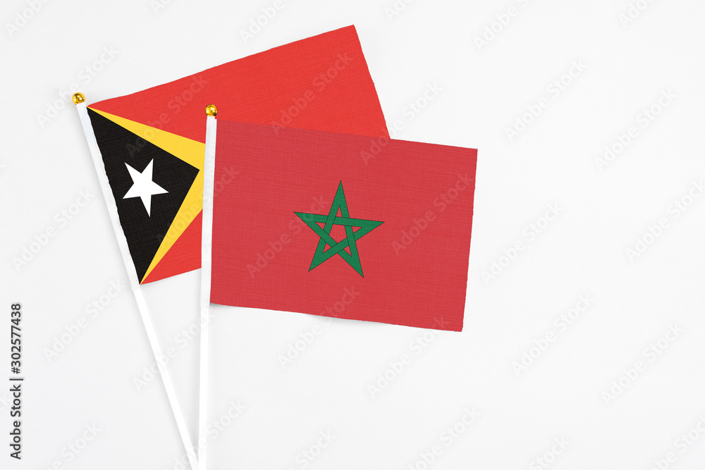 Morocco and East Timor stick flags on white background. High quality fabric, miniature national flag. Peaceful global concept.White floor for copy space. Morocco and East Timor stick flags on white background. High quality fabric, miniature national flag. Peaceful global concept.White floor for copy space.