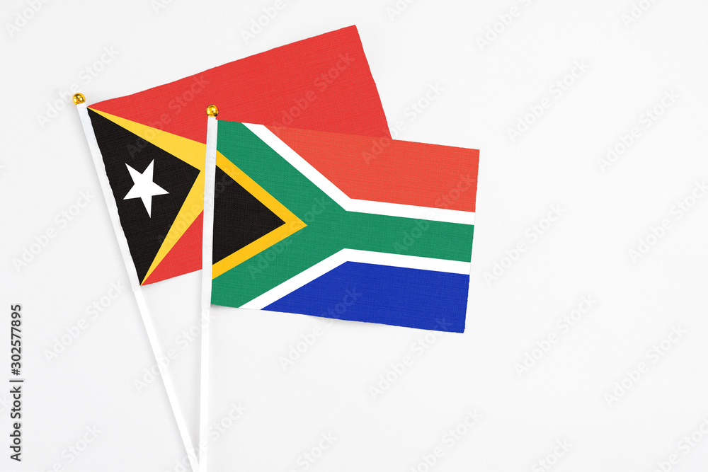 Fototapeta premium South Africa and East Timor stick flags on white background. High quality fabric, miniature national flag. Peaceful global concept.White floor for copy space.