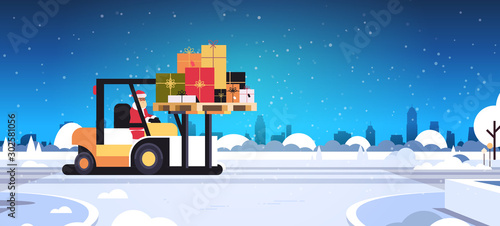 santa claus driving forklift truck loading colorful gift present boxes delivery and shipping concept merry christmas happy new year winter holidays celebration horizontal snowy sityscape background