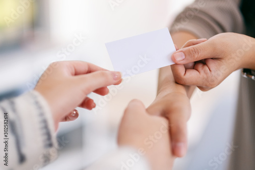 Two people shaking hands and exchanging empty business card