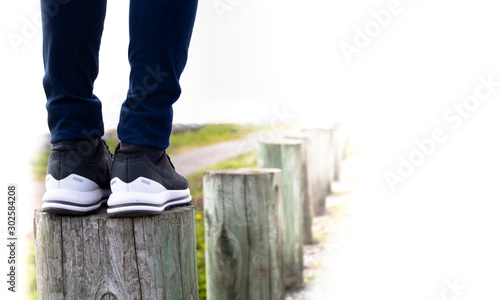 A woman standing on stump next to the road. Concept of living life with confidence and carefulness every steps of moving forward to make sure life safe. Free copyspace for text on right.