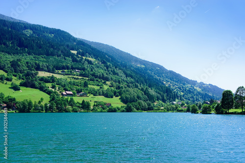 Panorama of lake Field am See in Carinthia at Austria. Landscape with pond and blue sky in spring or summer. Scenery in green Alps of Europe. Countryside with Alpine mountains. Nature with water © Roman Babakin