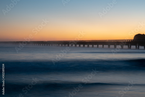 Spectacular colours of dawn over the ocean silhouetting Tolaga Bay historic wharf