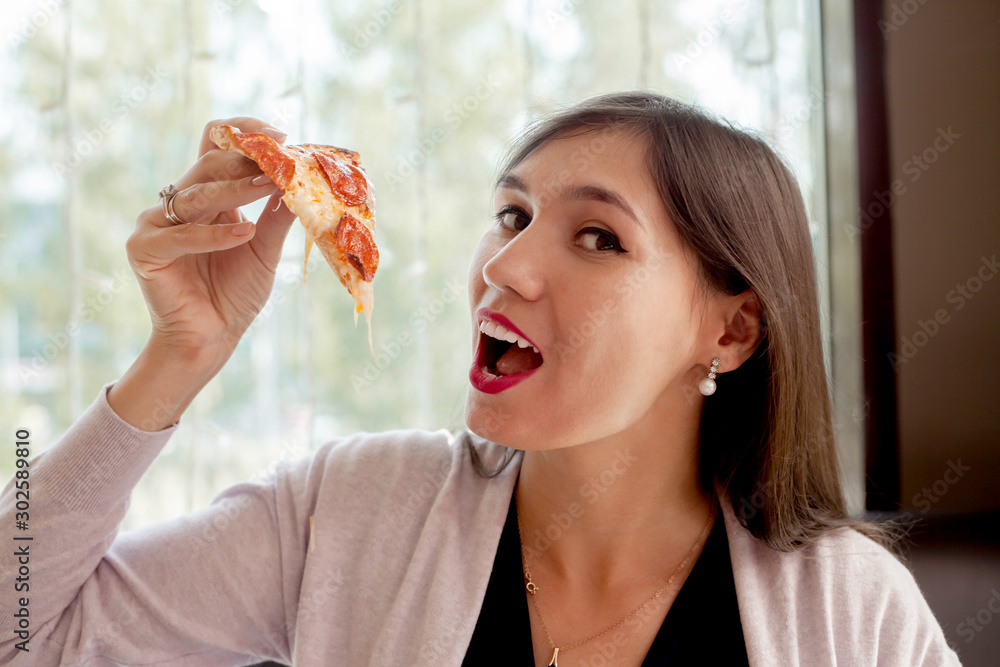 young woman eating pizza at a cafe