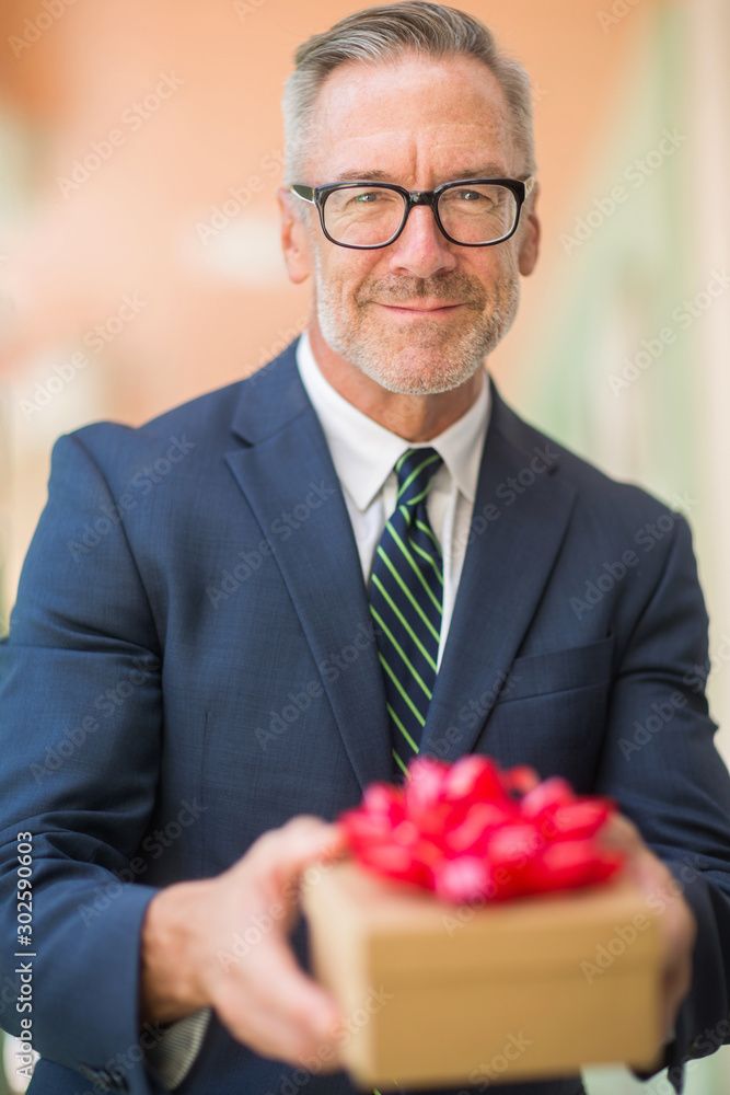 Mature handsome businessman holding a present. Mature handsome businessman holding a present.