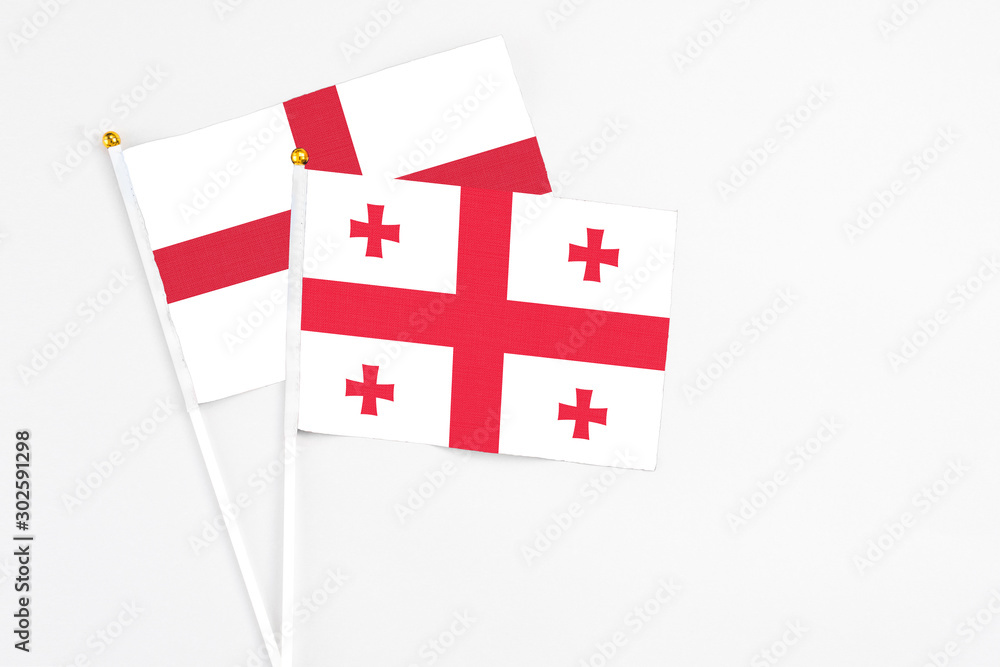 Georgia and England stick flags on white background. High quality fabric, miniature national flag. Peaceful global concept.White floor for copy space.