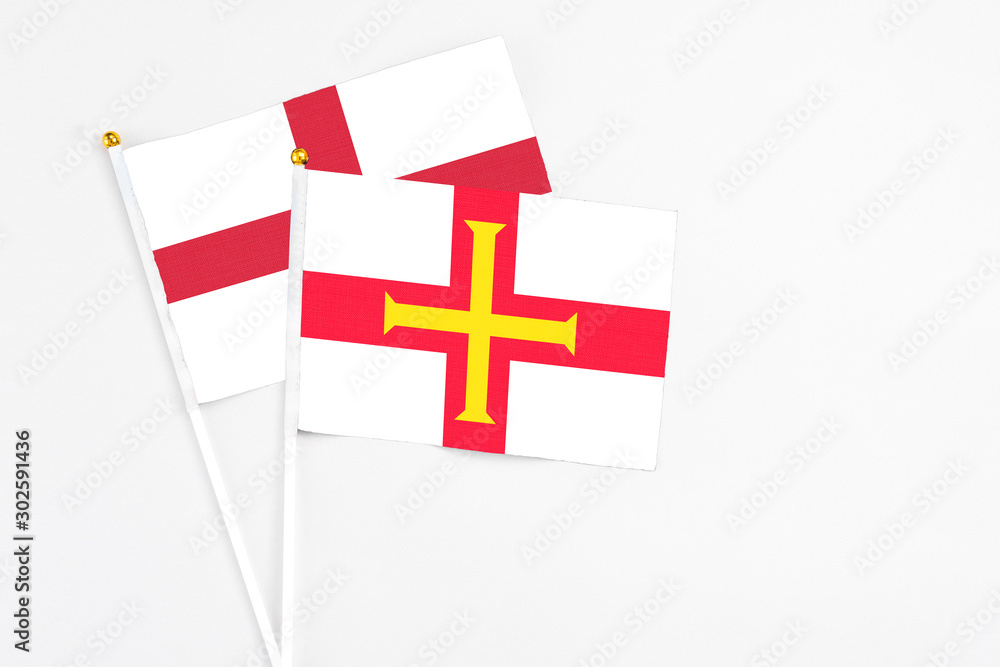 Guernsey and England stick flags on white background. High quality fabric, miniature national flag. Peaceful global concept.White floor for copy space.