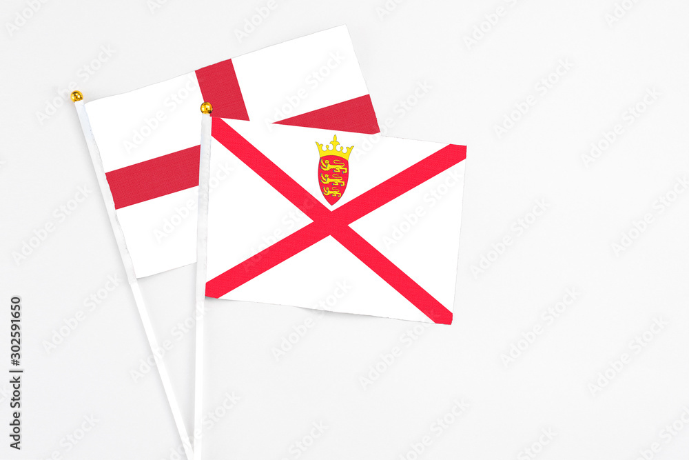 Jersey and England stick flags on white background. High quality fabric, miniature national flag. Peaceful global concept.White floor for copy space. Jersey and England stick flags on white background. High quality fabric, miniature national flag. Peaceful global concept.White floor for copy space.