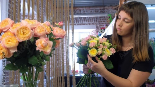Floral business concept. Portrait of professional woman florist making creating flowers bunch bouquet from different sorts of roses in flower shop. Working day in floristic studo store salon.