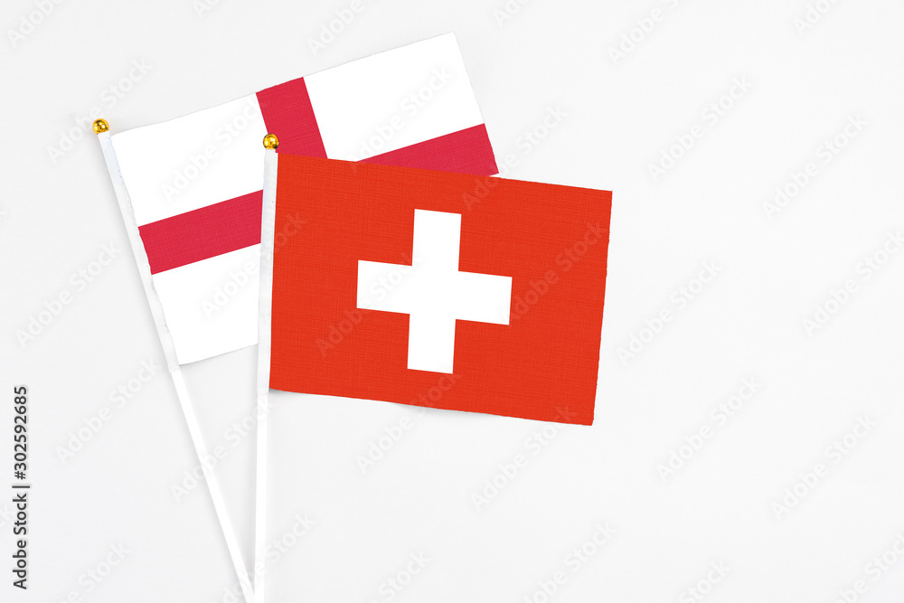 Switzerland and England stick flags on white background. High quality fabric, miniature national flag. Peaceful global concept.White floor for copy space.