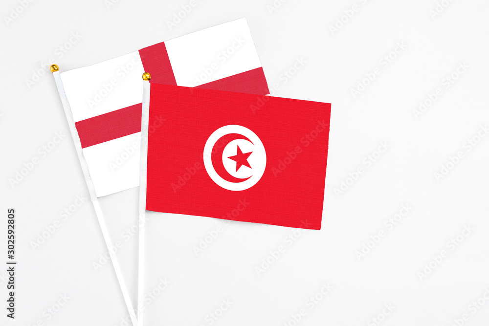 Tunisia and England stick flags on white background. High quality fabric, miniature national flag. Peaceful global concept.White floor for copy space.
