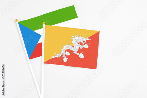 Bhutan and Equatorial Guinea stick flags on white background. High quality fabric, miniature national flag. Peaceful global concept.White floor for copy space.