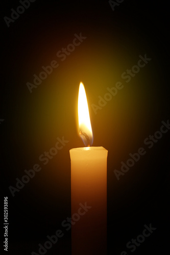 The candle burns on a black background. Concept Mourning. Sad events