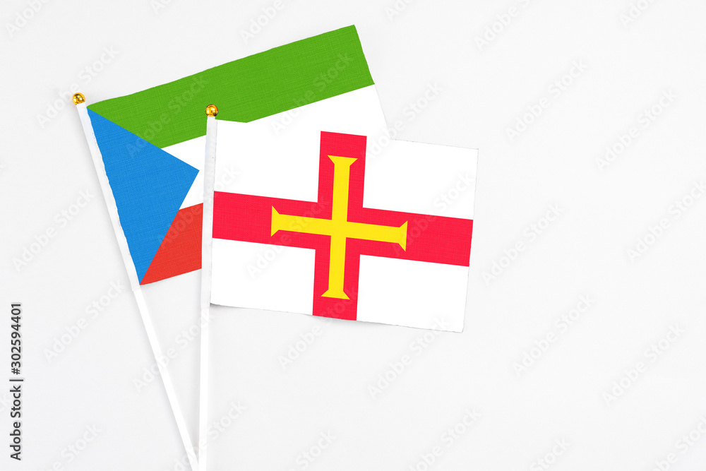 Guernsey and Equatorial Guinea stick flags on white background. High quality fabric, miniature national flag. Peaceful global concept.White floor for copy space.