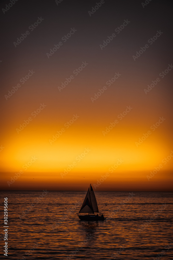 Sunset at Santa Monica pier: sailing boat on the horizon