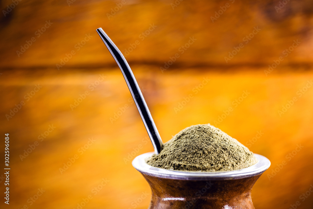 Yerba mate tea in wooden bowl on wooden table. Traditional drink from Brazil, Argentina, Paraguay and South America. - obrazy, fototapety, plakaty 