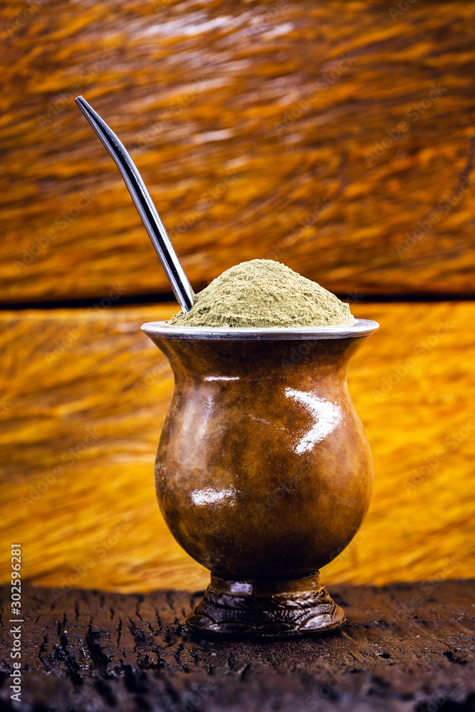 Foto Stock Gaucho yerba mate tea, the chimarão, typical brazilian drink,  traditionally in a cuiade bombilla stick gourd against wooden background.  Rio Grande do Sul, preferred drink of the gauchos. | Adobe