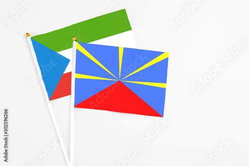 Reunion and Equatorial Guinea stick flags on white background. High quality fabric, miniature national flag. Peaceful global concept.White floor for copy space.