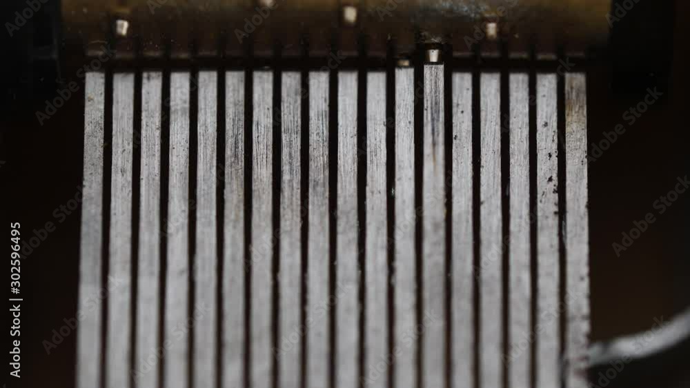 Top-down macro view of the inside of an old music box as drum spins and the tiny pins pluck the teeth of the comb. Top-down macro view of the inside of an old music box as drum spins and the tiny pins pluck the teeth of the comb.
