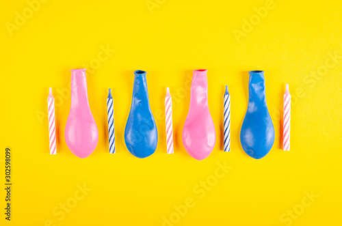 Colored candles and air balloons composition on yellow background, party and celebration decoration.