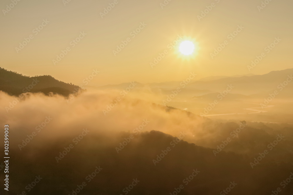 Mountain view morning of soft mist moving around top hill with sea of fog and yellow sun light in the sky background, sunrise at Wat Tha Ton, Tha Ton, Fang, Chiang Mai, Thailand.