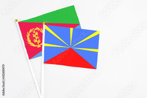 Reunion and Eritrea stick flags on white background. High quality fabric, miniature national flag. Peaceful global concept.White floor for copy space.